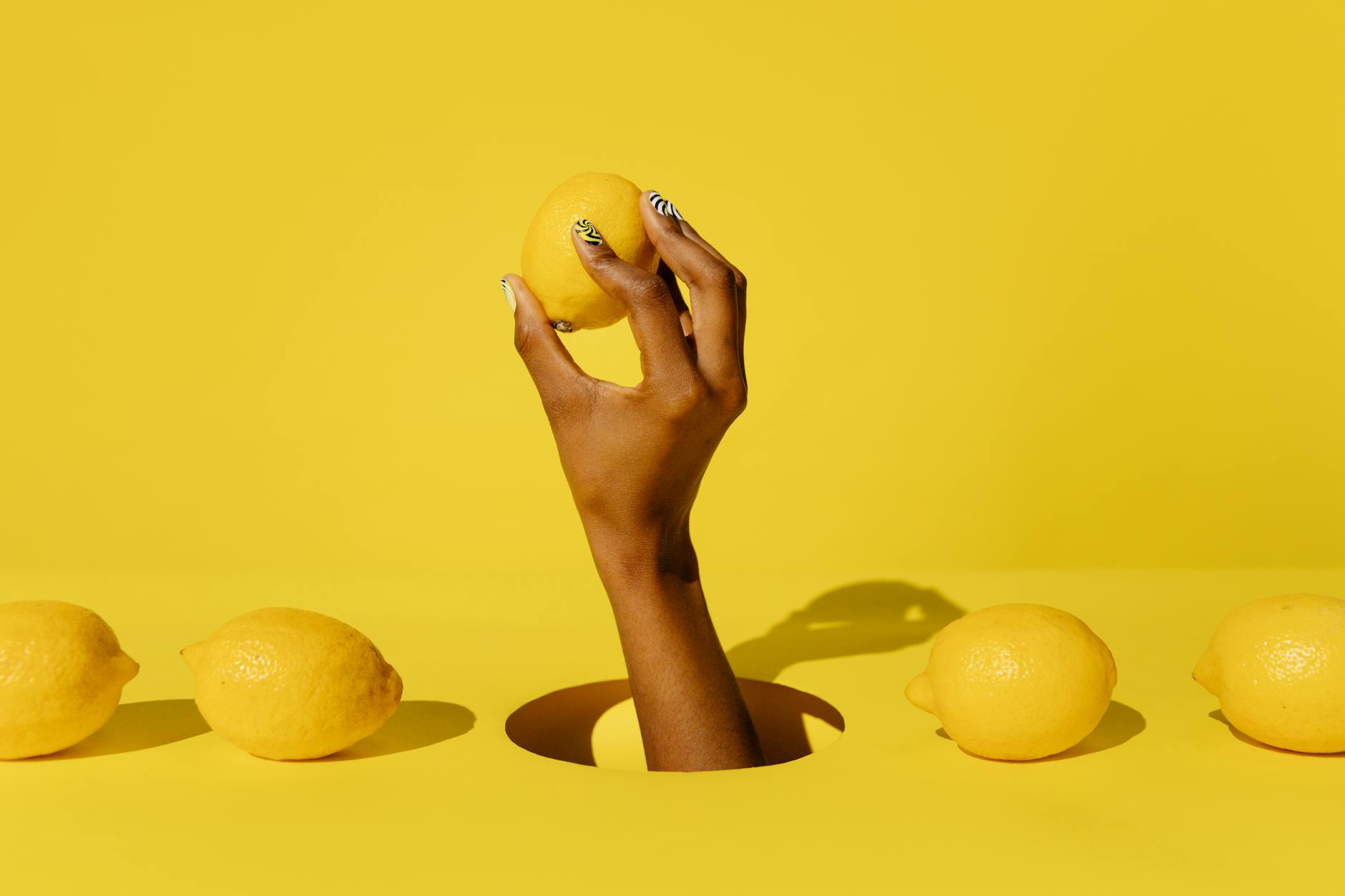 A hand holding a fresh lemon against a vivid yellow background, symbolizing renewed freshness and returning sensation