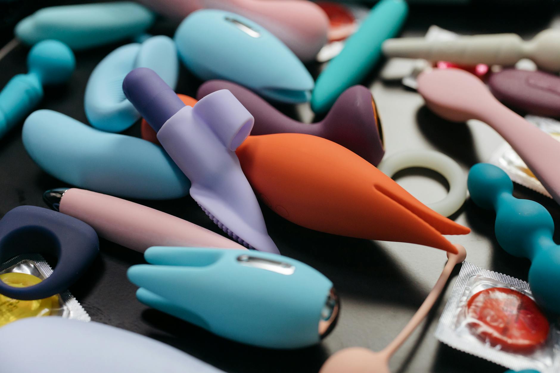Colorful sex toys arranged on a bright yellow background, featuring various designs and shapes.