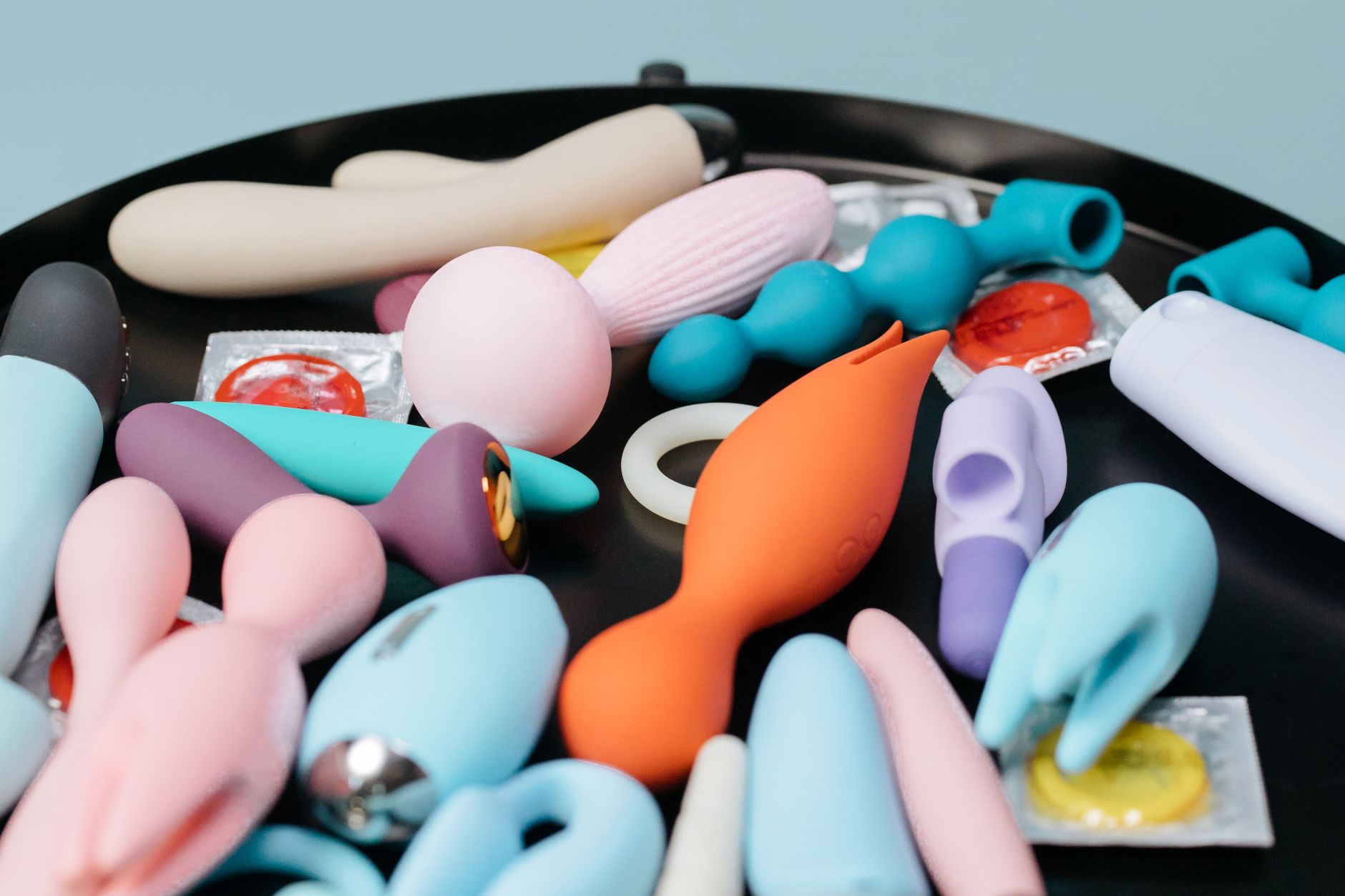 Vibrant collection of colorful sex toys on a black tray