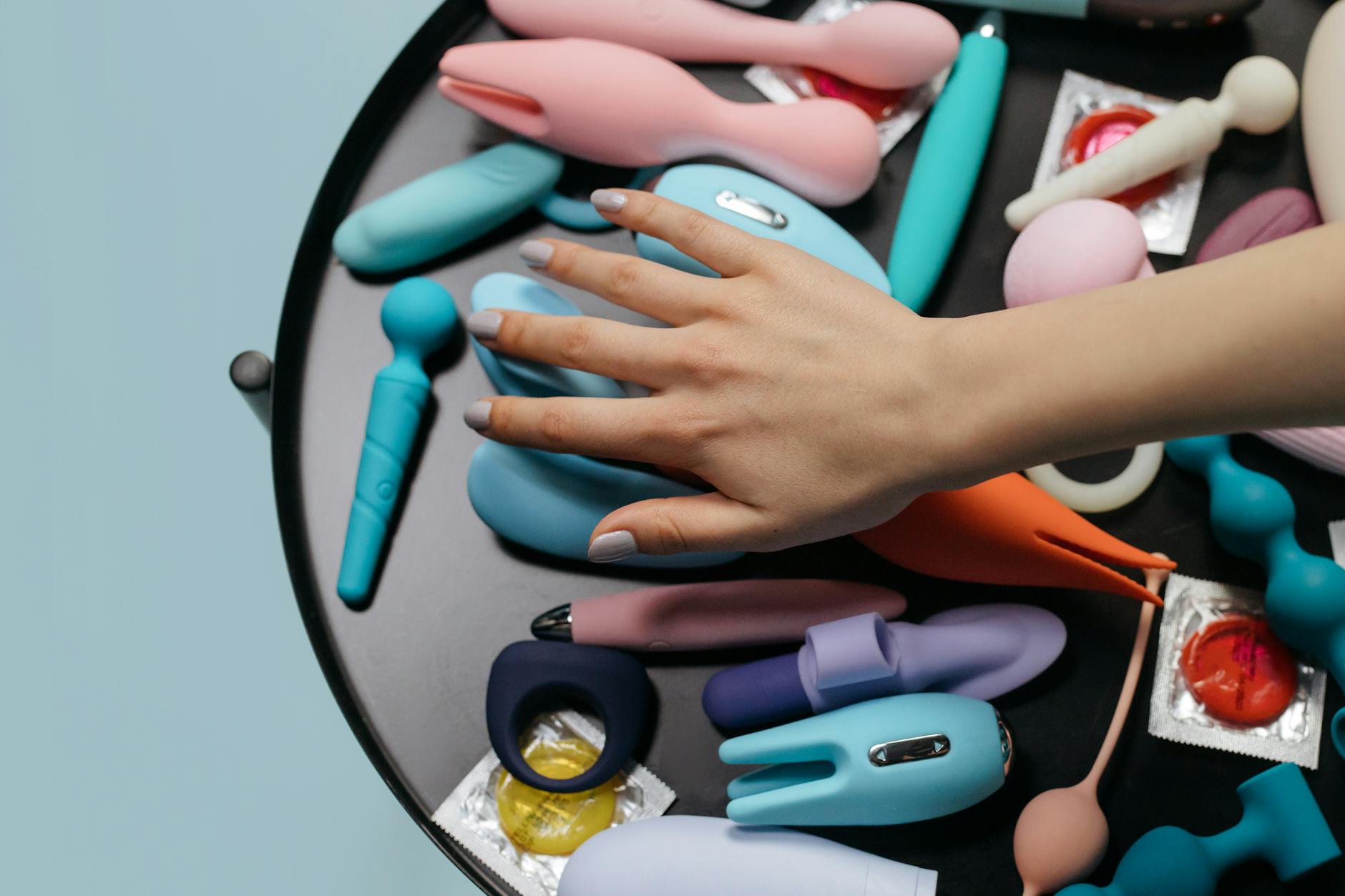 A hand reaching over a variety of colorful vibrators arranged on a display surface
