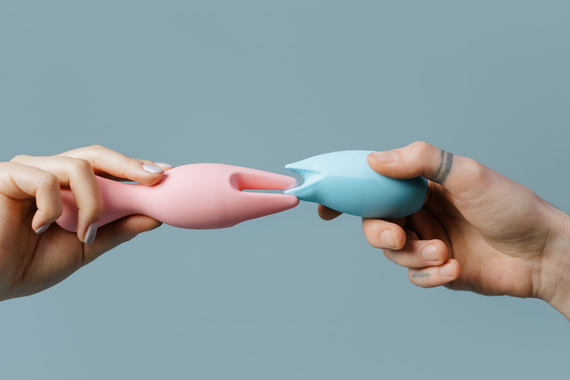 Hands holding pastel-colored silicone toys on a soft surface