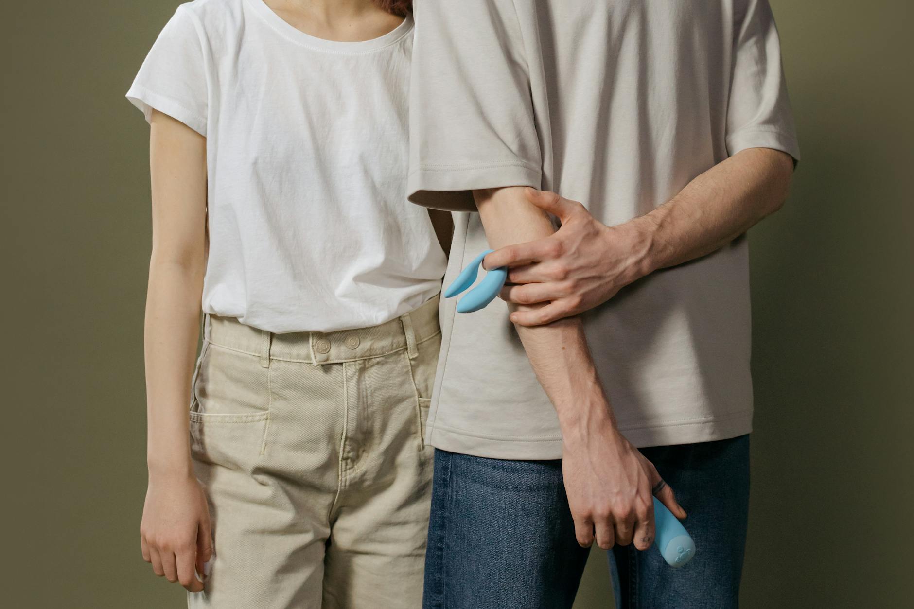A couple holding a blue vibrator together, representing modern intimacy and adaptation